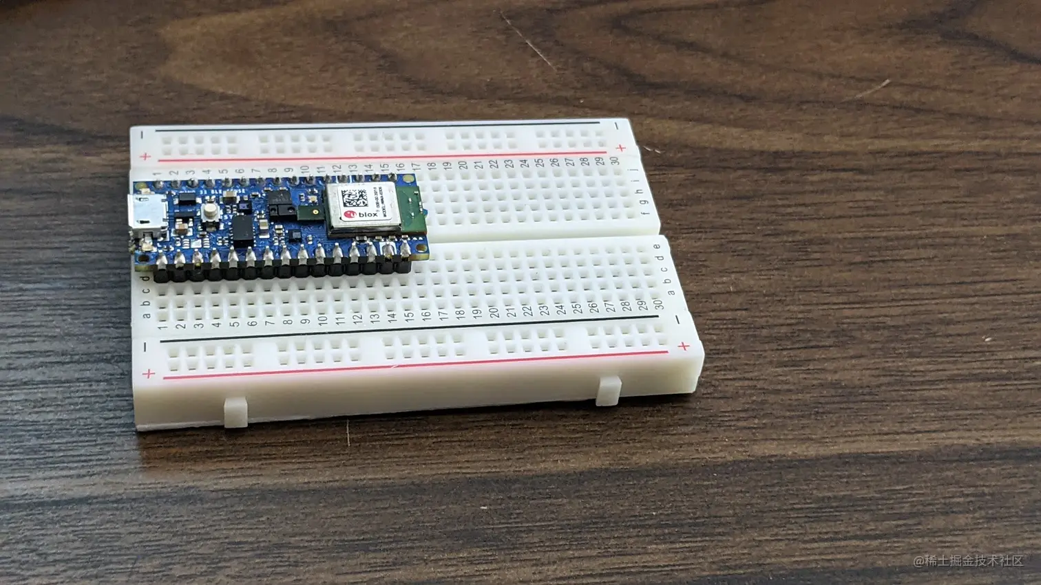 Image of the Arduino Nano 33 BLE sense slotted into a solderless breadboard. Note that one set of headers is to the left of the main channel that runs down the center of the board and the second set of headers is to the right of that main channel.