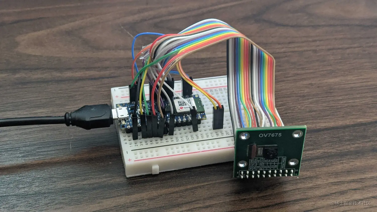 The Arduino Nano 33 BLE sense on a breadboard connected to the OV7675 camera through jumper wires showing a USB cable attached to the Arduino.