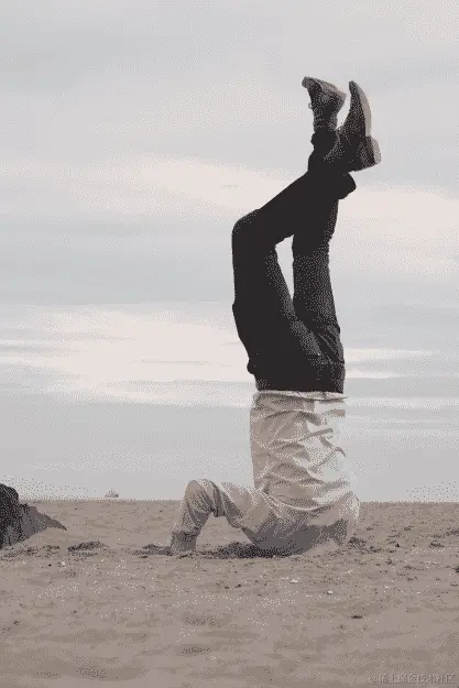 一位衣着整洁的男子，头和手埋在沙滩上的照片。