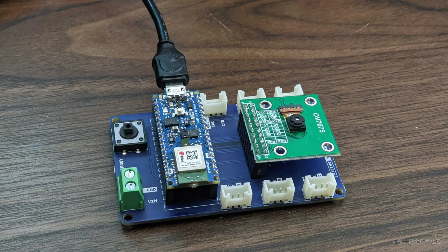 Image of the tinyML shield with the Arduino Nano 33 BLE sense and Arducam OV7675 slotted in place and the USB cable connected to the Arduino.