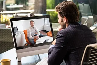 一个男子对着显示器进行视频会议